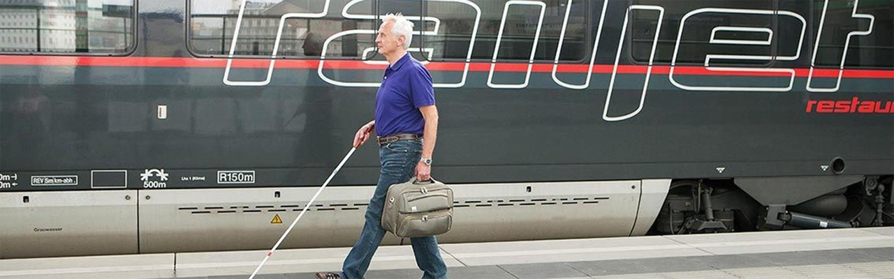 Mann mit Blindenstock am Bahnsteig