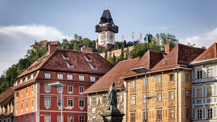 Häuser in Graz mit Uhrturm im Hintergrund