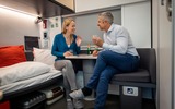 Coppia che parla nel vagone letto comfort plus davanti a un bicchiere di spumante