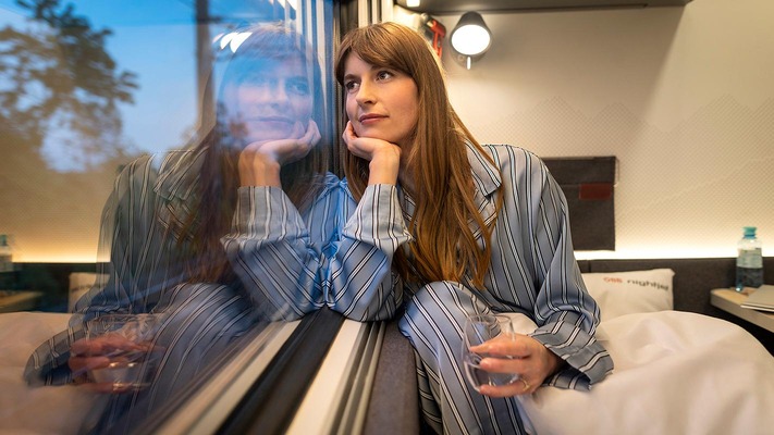 Woman in the comfort plus sleeping car looks dreamily out of the window