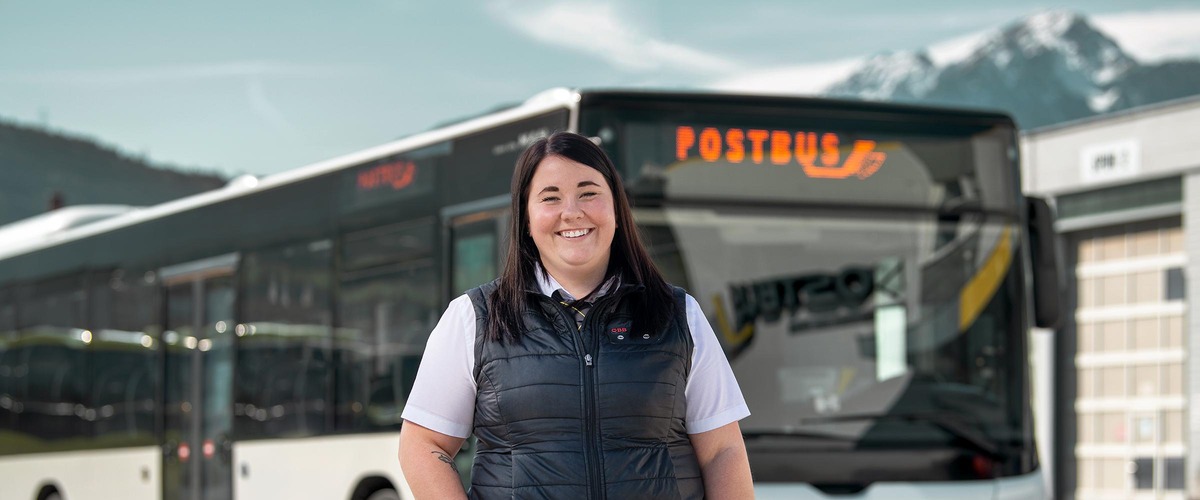 Postbuslenkerin vor einem Postbus