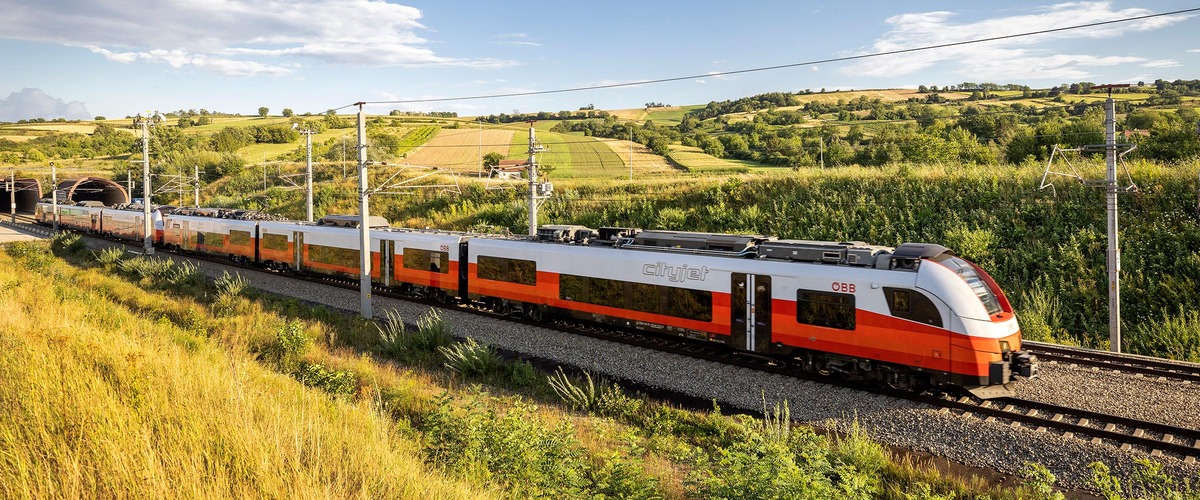 Cityjet in herbstlicher Landschaft fährt aus Tunnel
