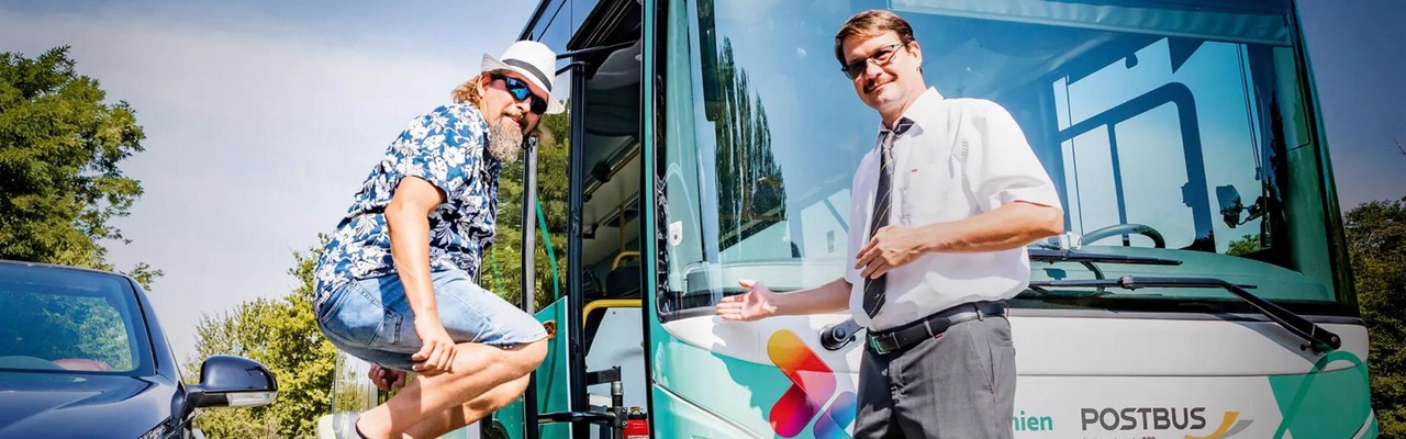 Busfahrer und Fahrgast stehen vor Postbus