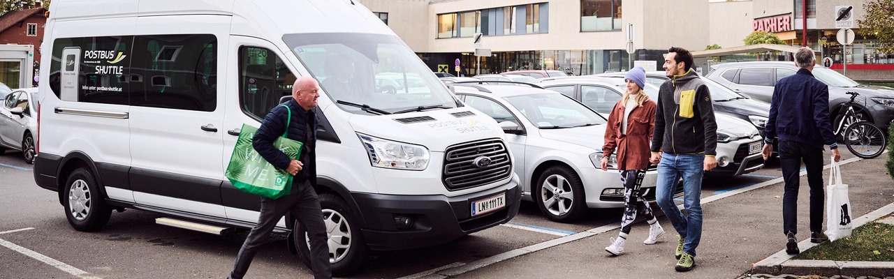 Fahrer und Kundin stehen vor Postbus Shuttle