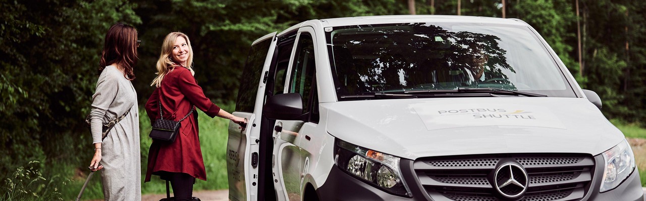 Frauen steigen ins Postbus Shuttle
