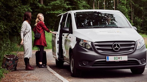 Frauen steigen in Postbus Shuttle