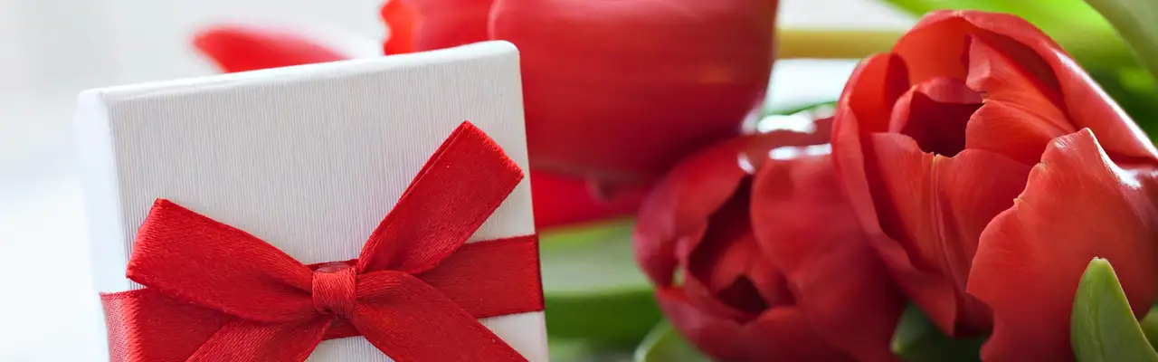 Geschenk und Tulpen auf Holz