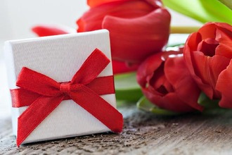 Geschenk und Tulpen auf Holz
