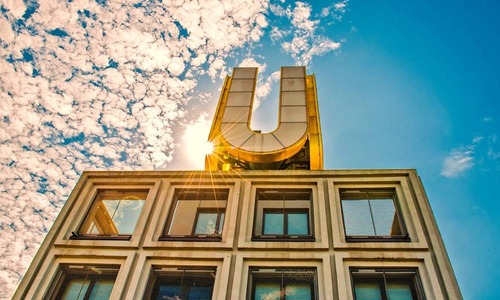Das in Dortmund aufgenommene Foto zeigt das Gebäude "Dortmunder U". Auf dem Gebäude befindet sich ein großer Buchstabe "U", durch den die Sonne scheint. Der Himmel ist blau mit vereinzelten Wolken. <br/>