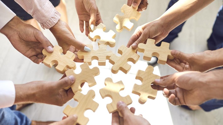 company employees playing game and joining pieces of jigsaw puzzle during team building activity