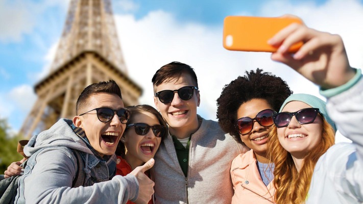 smiling friends taking selfie with smartphone