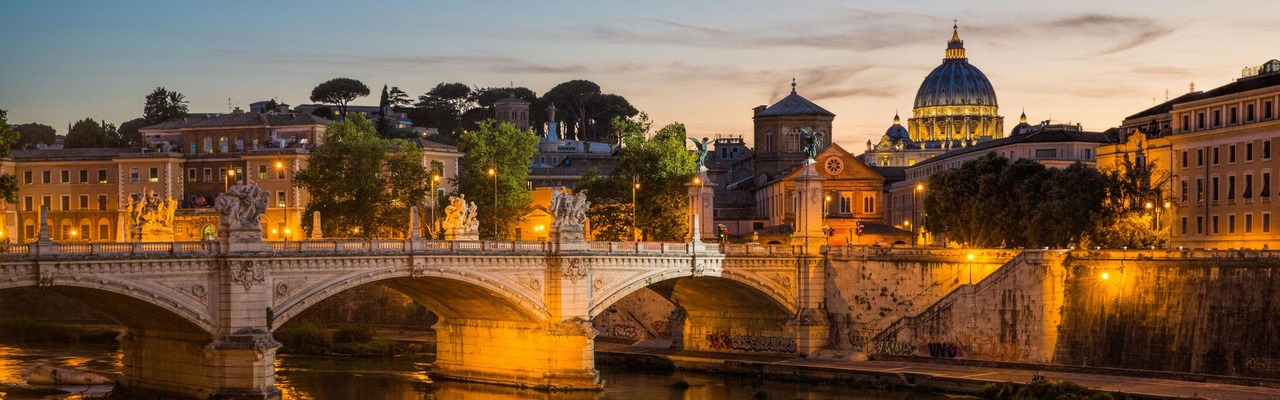 View of St Peter's Cathedral and the Tiber river from Pont Sant'Angelo at dusk