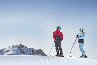 Skifahrer auf Piste vor Bergpanorama