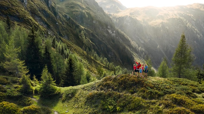 Wanderer in den Bergen vor blühenden Wiesen