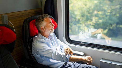 Mann im Businessabteil sieht aus Fenster hinaus