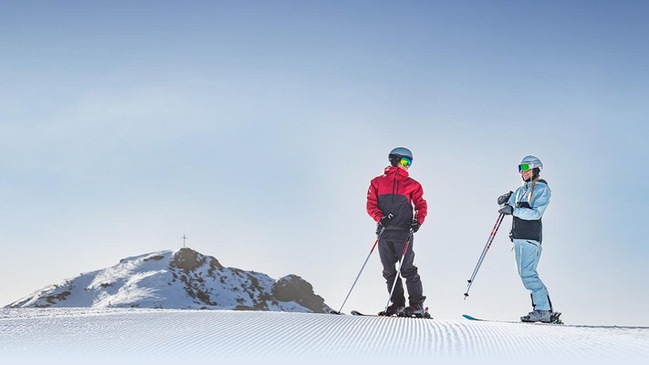 Skifahrer auf Piste vor Bergpanorama