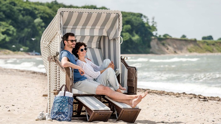Paar entspannt im Strandkorb auf dem Ostseestrand