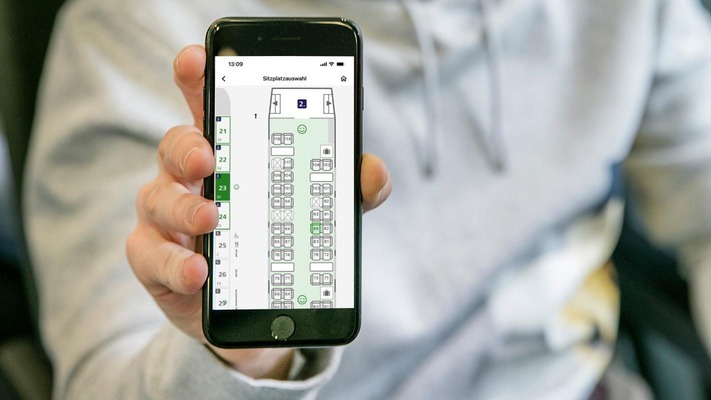 Kunde hält Smartphone mit grafischer Sitzplatzreservierung