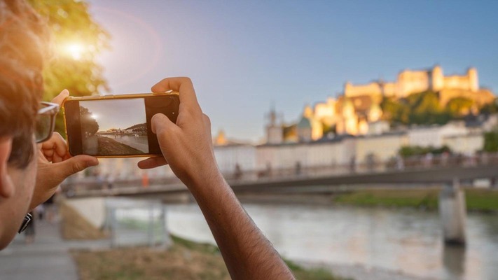 Person fotographiert Salzburg Stadt mit Smartphone