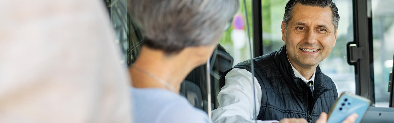 Fahrgast zeigt Busfahrer Ticket am Handy