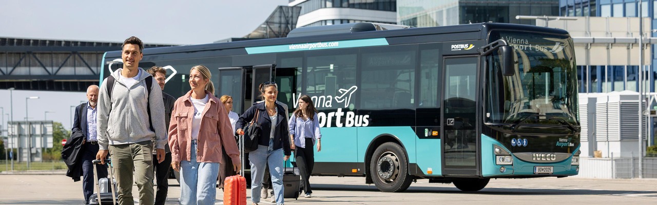 Personen mit Gepäck vor Vienna Airport Bus