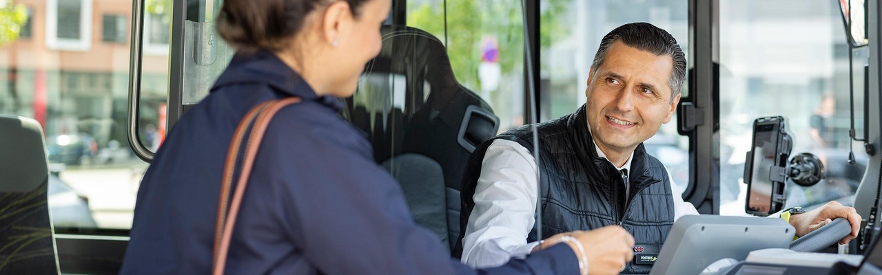 Frau im Bus zeigt Busfahrer ihr Ticket