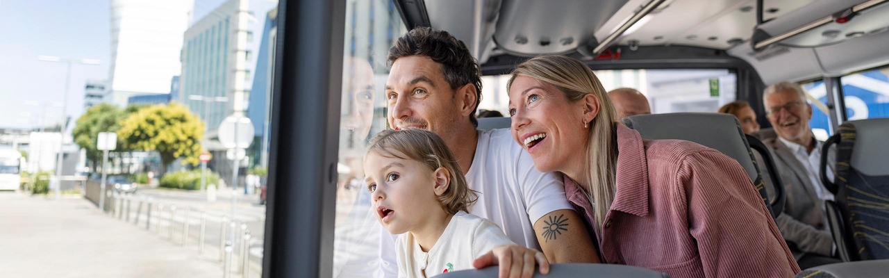 Familie sitzt im Bus und sieht aus dem Fenster