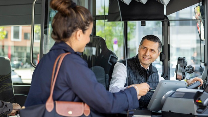 Frau im Bus zeigt Busfahrer ihr Ticket