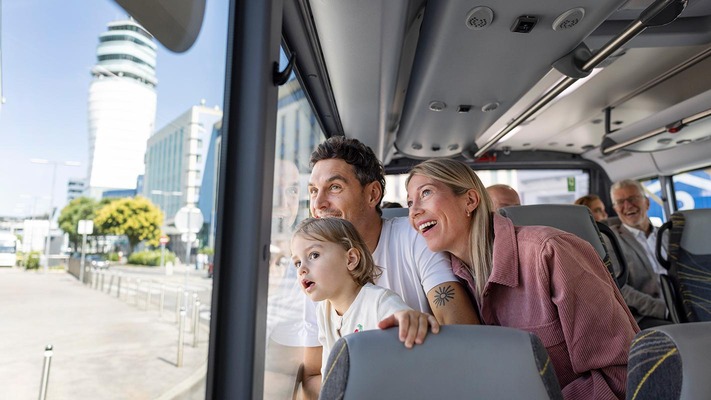 Familie sitzt im Bus und sieht aus dem Fenster