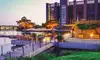 Abendstimmung in der Autostadt Wolfsburg mit beleuchteten Gebäuden, Wasserflächen und einer modernen Promenade mit Sitzbereichen und Gastronomie.