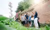 Stadtführerin erklärt einer Besuchergruppe vor hoher Ziegelmauer, daneben moderner Aussichtsturm mit offener Wendeltreppe<br/><br/>