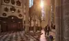 In einer Kirche mit hohen Säulen und bunten Fenstern betrachtet ein Paar ein reich verziertes steinernes Chorgestühl<br/>
