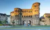 Das römische Stadttor Porta Nigra wird von warmem Abendlicht beleuchtet, umgeben von historischen und modernen Gebäuden