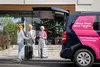 Menschen mit Reisekoffer stehen neben ÖBB Transfer Shuttle