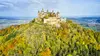 Die Burg Hohenzollern liegt auf einem Hügel und ist von vielen bunten Bäumen umgeben