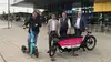Personen präsentieren Lastenrad und E-Scooter vor Bahnhofsgebäude