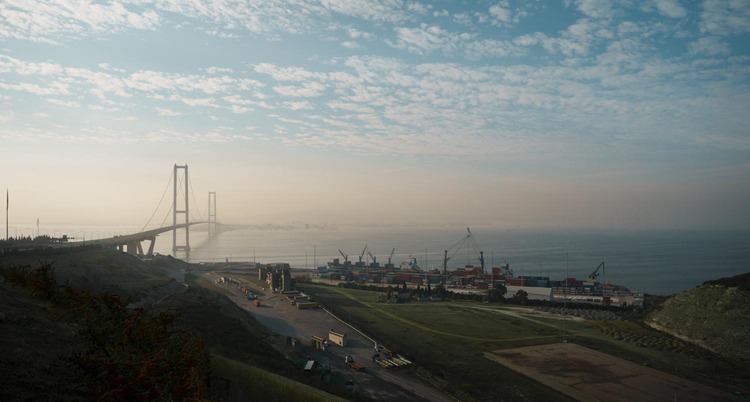 Bridge in Turkey overlooking a coastal container port with cranes and stacked containers