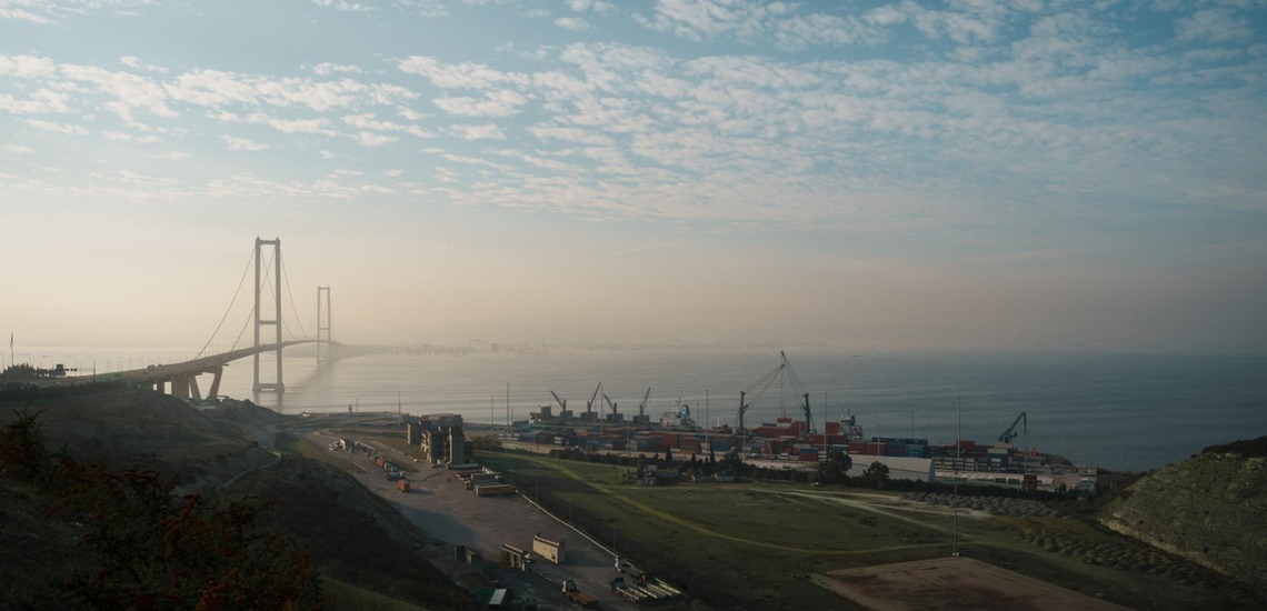 Brücke in der Türkei über Küstengewässer nahe eines Containerterminals mit Kränen und Containern