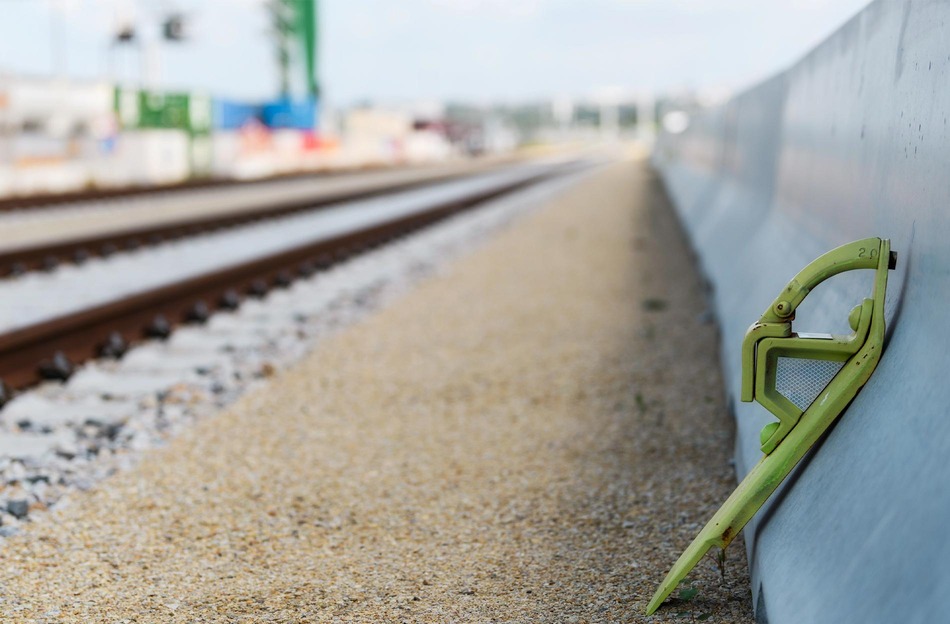 Grüner Hemmschuh an einem Güterwagen neben Gleisen im Terminal