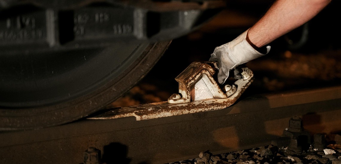 Hemmschuh wird am Rad eines Güterwagens auf dem Gleis angebracht