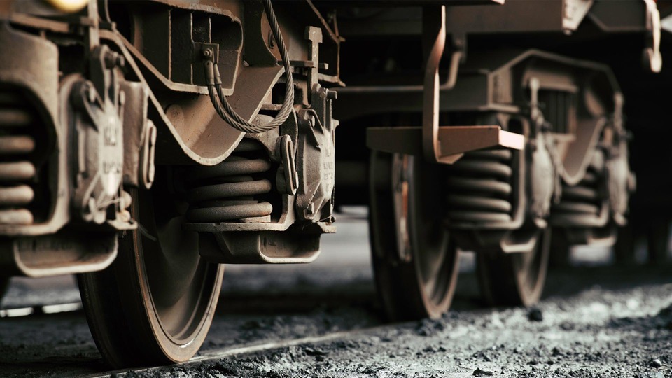 Close-up of freight wagon wheels and suspension system on railway tracks