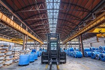 Warehouse Desio with forklift in the center and stacked blue steel coils under a tall hall structure