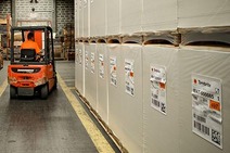 Forklift moving large stacks of paper reels in a warehouse