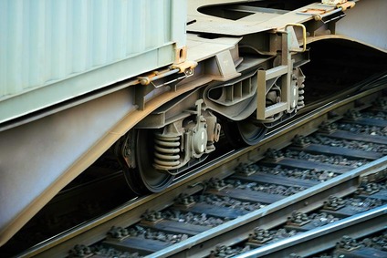 Detailaufnahme eines Güterwagen-Drehgestells mit Container auf den Schienen.