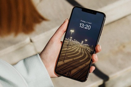 Hand holding a smartphone showing a lit freight rail yard at night on the screen