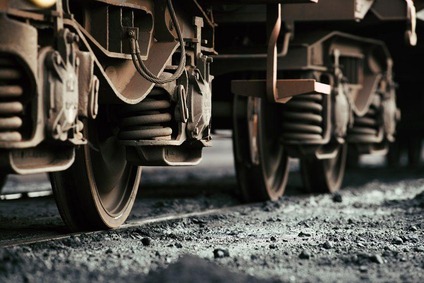Close-up of freight wagon wheels with steel springs on gravel track.