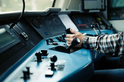 Train driver operating the locomotive from the modern control desk in the cab.