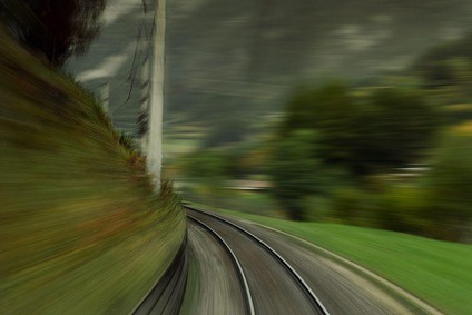 Blurred railway tracks in a curve, seen from a moving train.