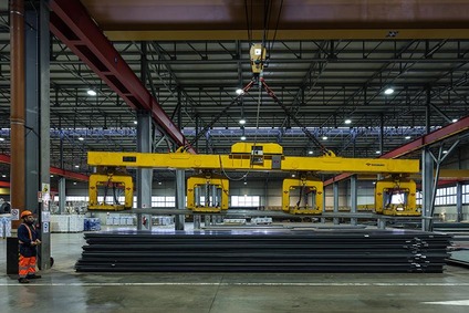 Heavy-duty crane lifting steel beams in Rail Cargo Group warehouse in Italy