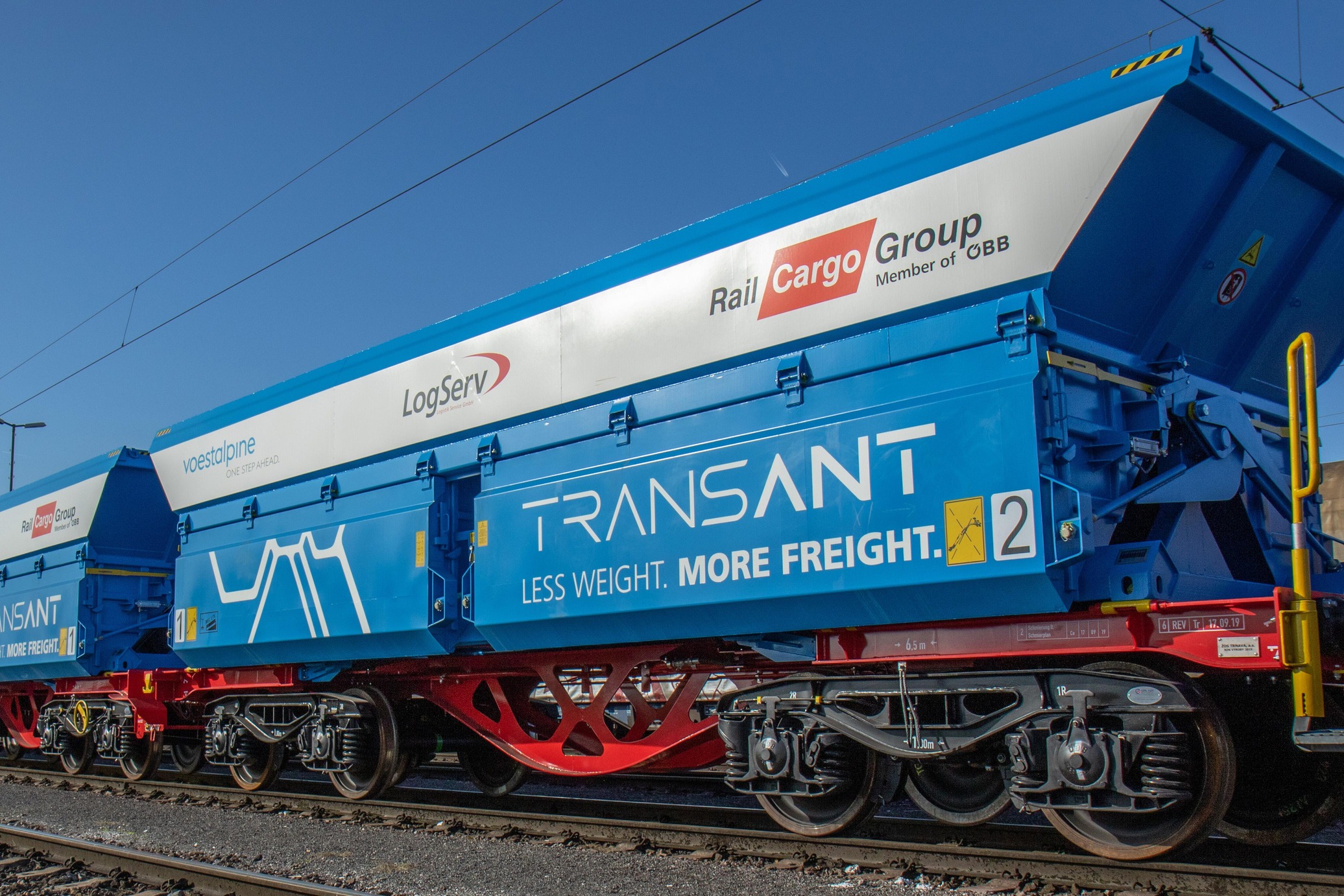 Blue TransANT freight wagon on railway tracks.